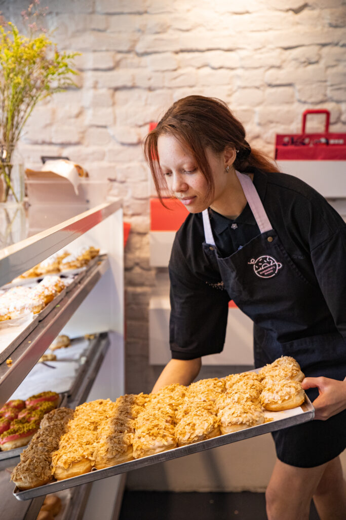 Our FOH team member Alisha placing a tray of Bienenstich donuts in our display in one of our shops.